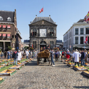 Gouda, Netherlands, August 25, 2022: Cheese market on the central market square with a view of the Goudse Waag weighing house, built in 1668.